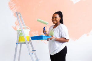 Happy,African,American,Woman,Painting,Wall,In,Her,New,Apartment.